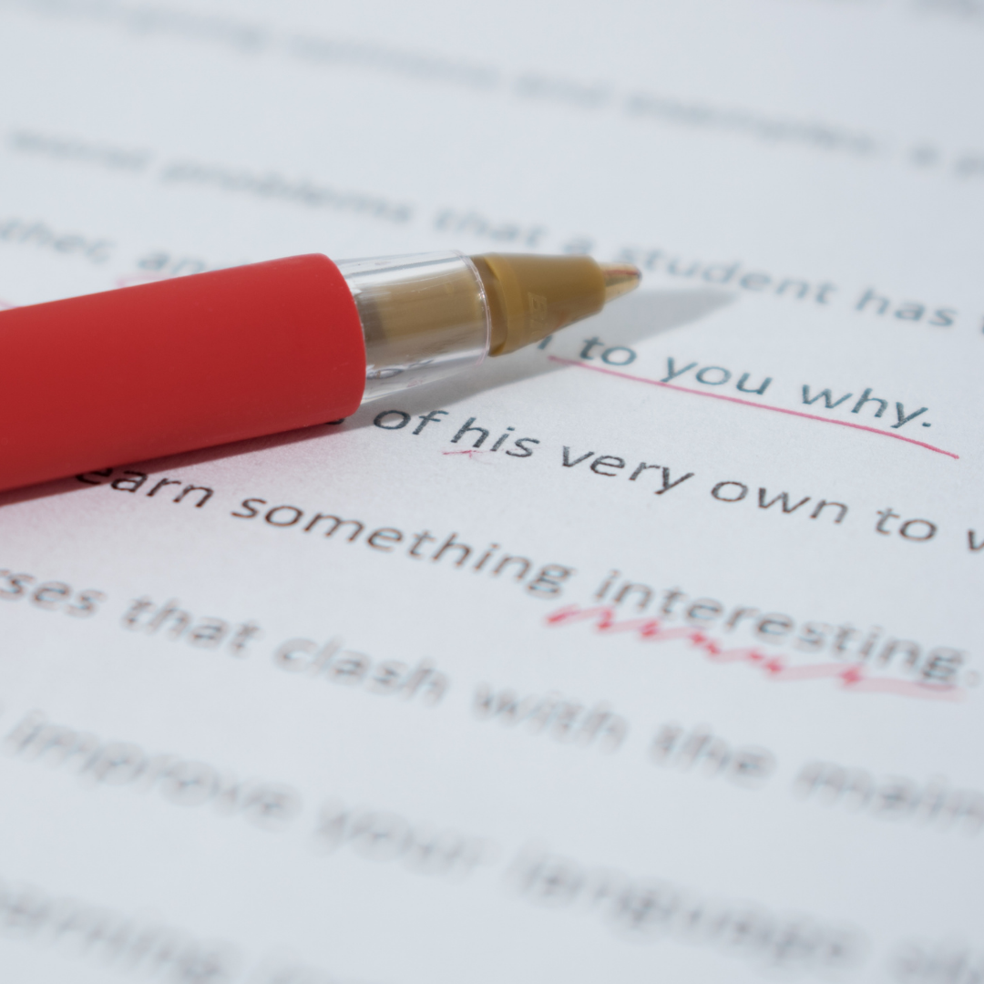 Red pen on top of a typed essay with words underlined in red
