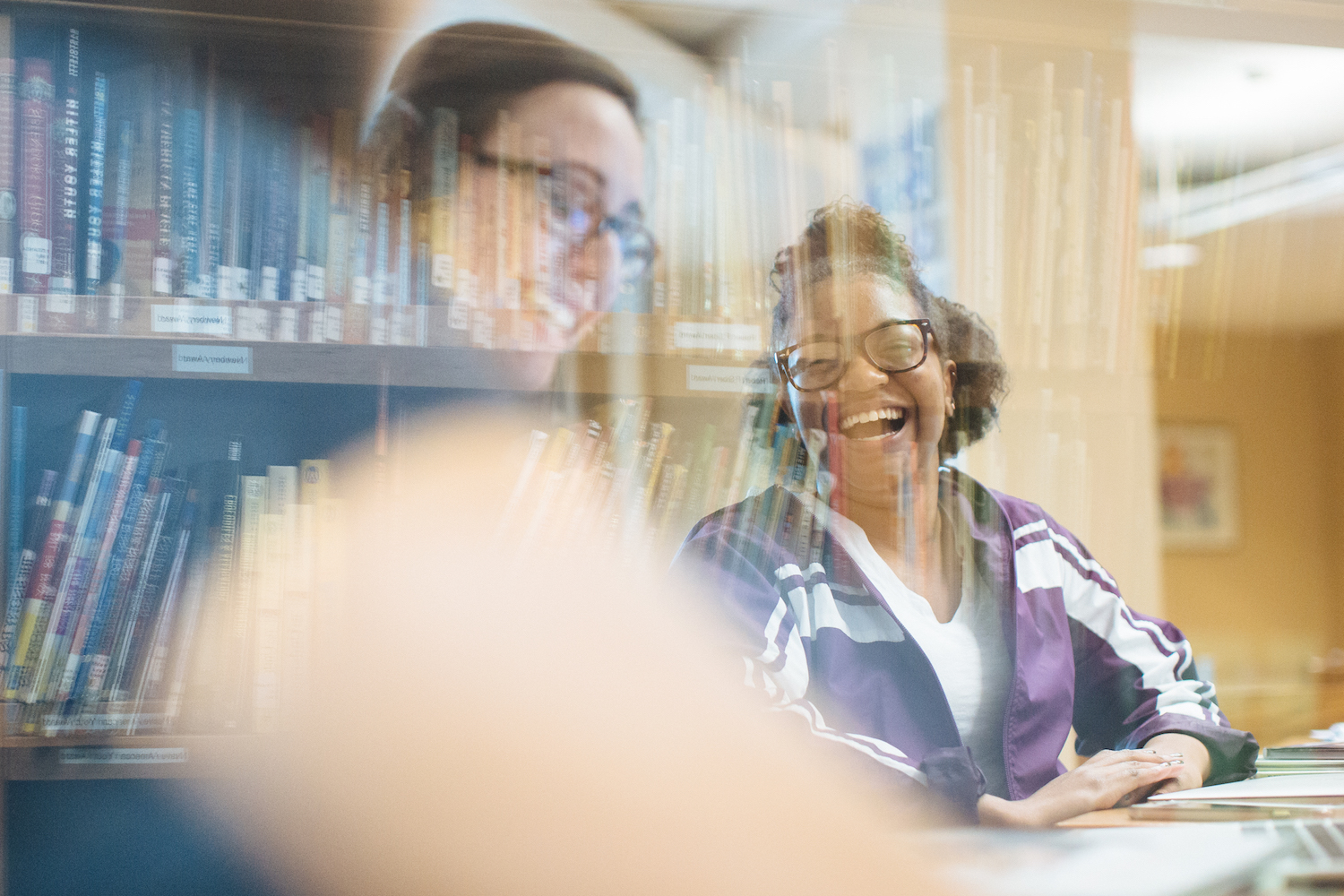 hybrid photo blending image of bookshelves with two students smiling in glasses