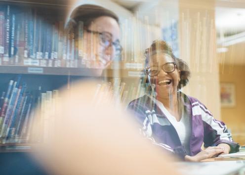 hybrid image of library books blurred with two students smiling and wearing glasses